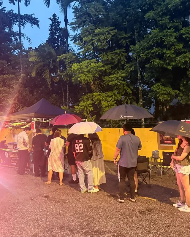 Customers queueing with umbrellas at the stall in the rain